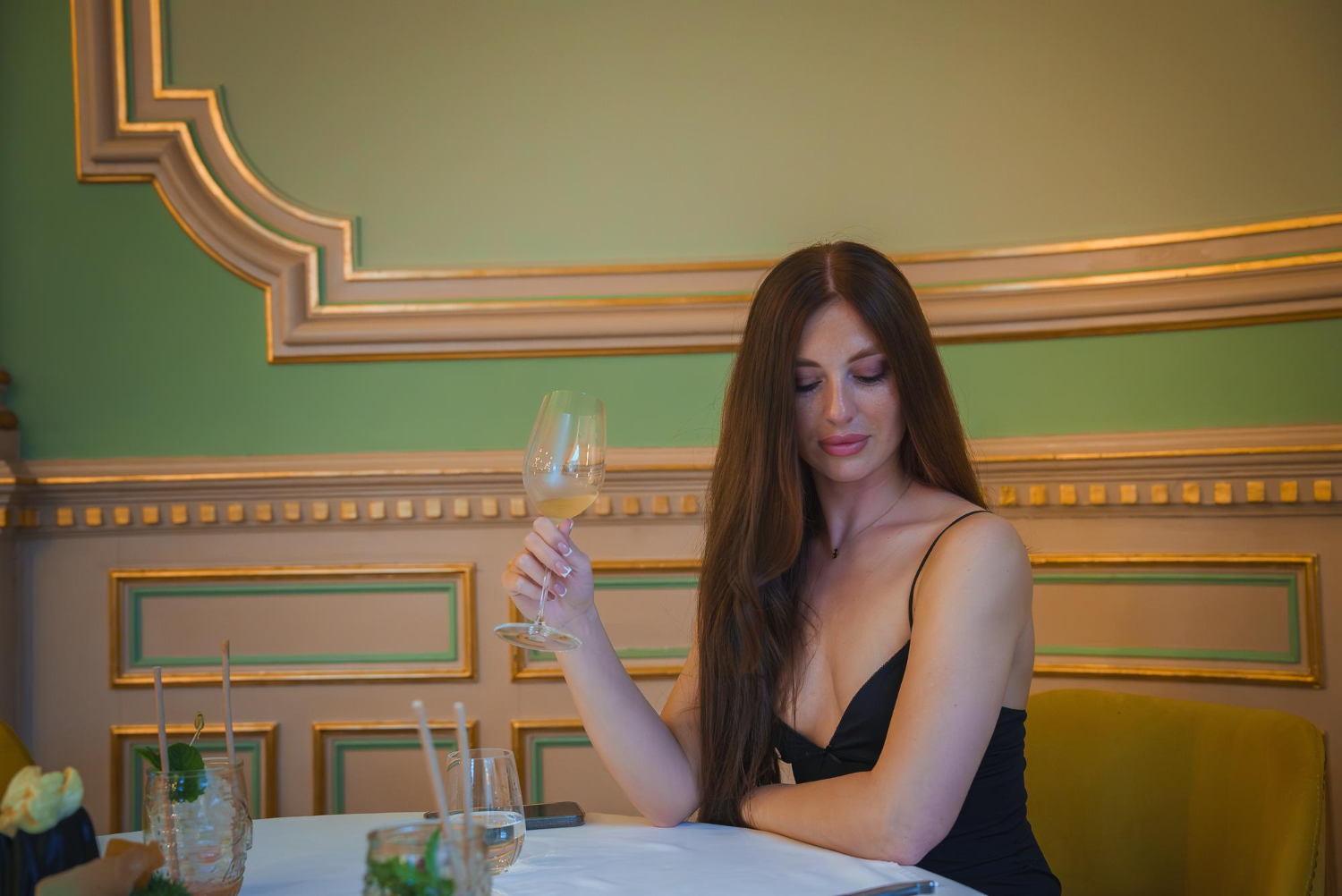 девушка сидит за столиком с бокалом в руке