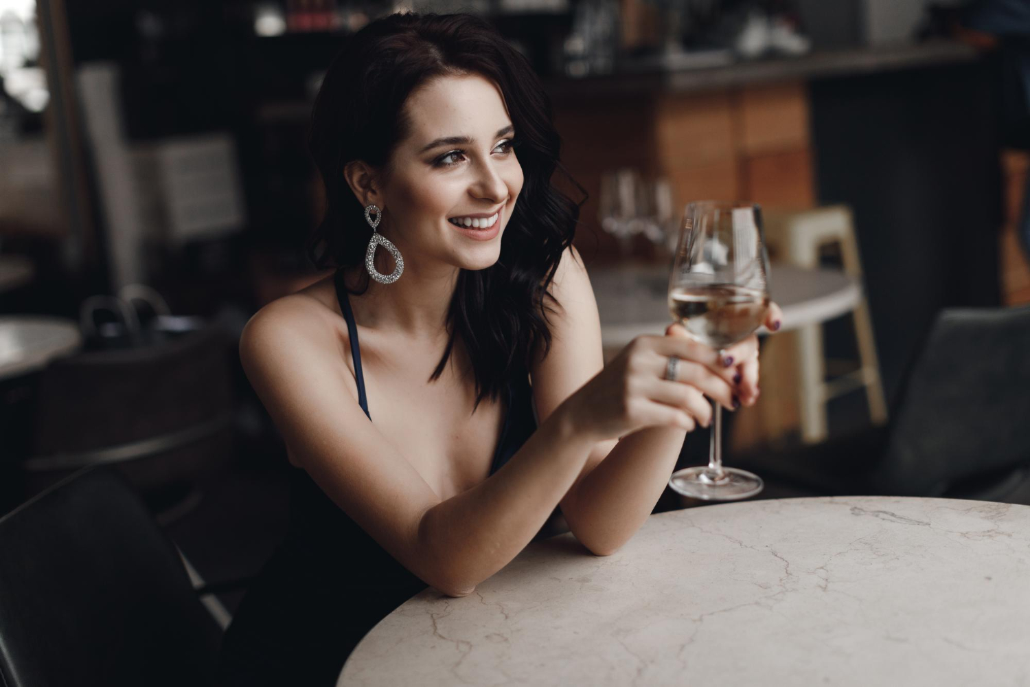 девушка сидит с бокалом и смеется